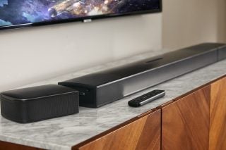 Black JBL bar 9.1 soundbar and speaker placed on a table below and in front of a TV